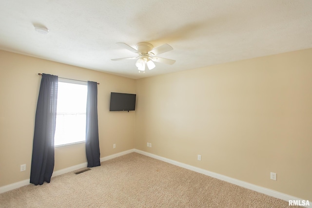 empty room with ceiling fan, light carpet, visible vents, and baseboards