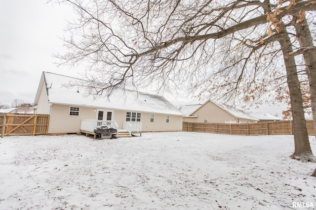 snow covered back of property featuring a fenced backyard and a wooden deck