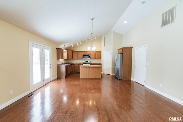 kitchen featuring stainless steel appliances, a kitchen island, visible vents, brown cabinets, and decorative light fixtures