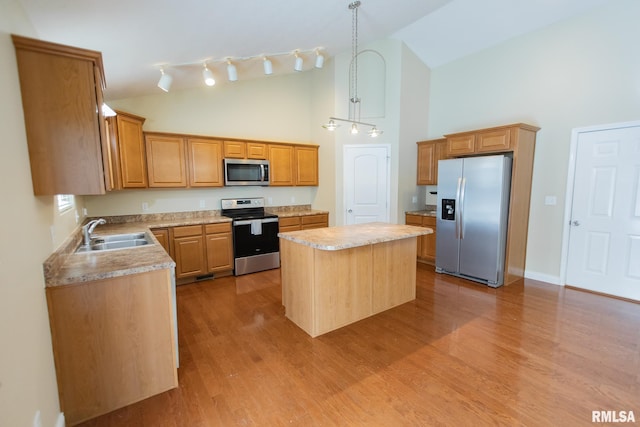 kitchen with light countertops, hanging light fixtures, appliances with stainless steel finishes, a kitchen island, and a sink