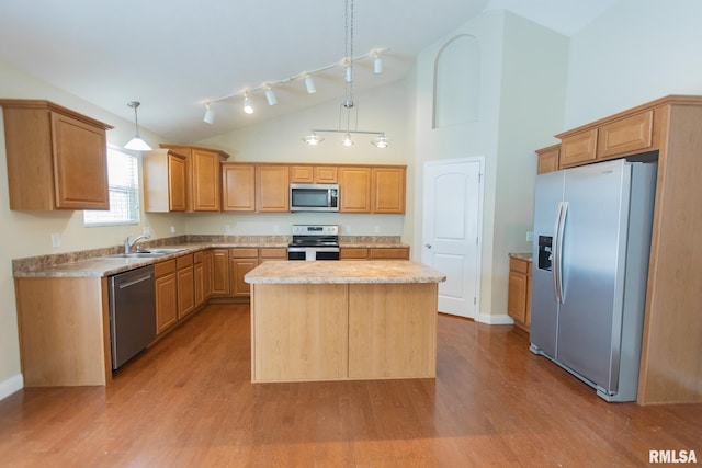 kitchen with light wood-style flooring, hanging light fixtures, appliances with stainless steel finishes, light countertops, and a center island