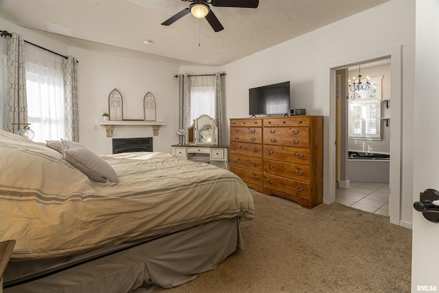 bedroom with light carpet, light tile patterned floors, ensuite bath, and a ceiling fan