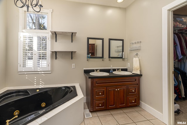 full bathroom featuring a walk in closet, a sink, a tub with jets, and tile patterned floors