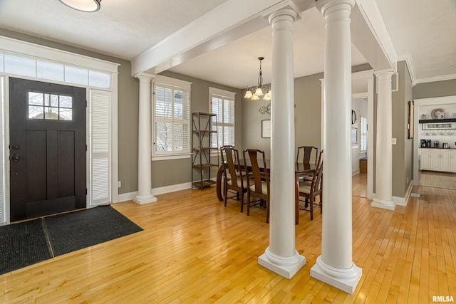 entrance foyer featuring baseboards, light wood finished floors, and ornate columns