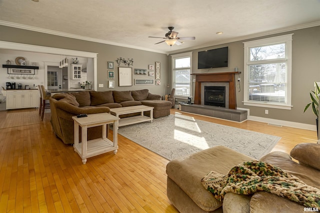 living area featuring visible vents, a tiled fireplace, ornamental molding, wood finished floors, and baseboards