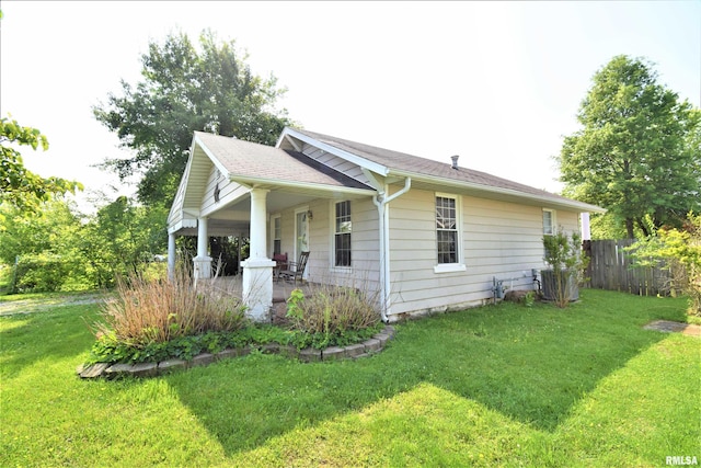 view of side of home with a porch, a lawn, and fence