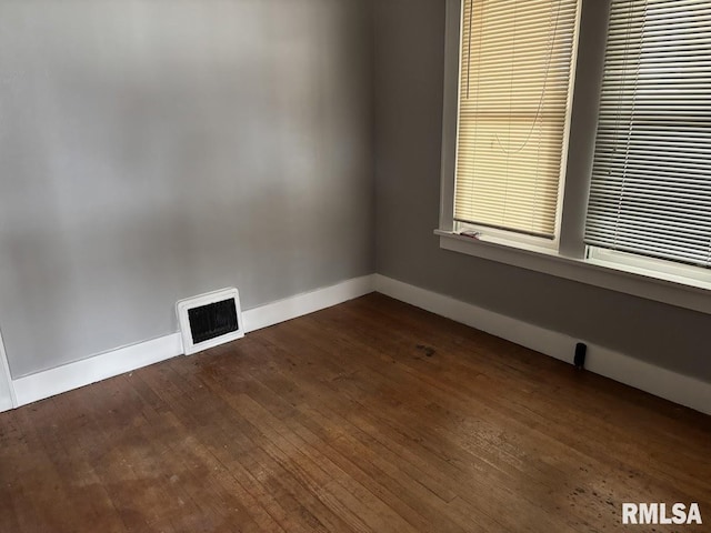 unfurnished room featuring dark wood-style floors, baseboards, and visible vents