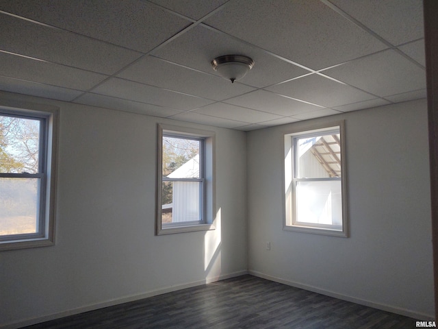 unfurnished room featuring a paneled ceiling, baseboards, and dark wood-style flooring