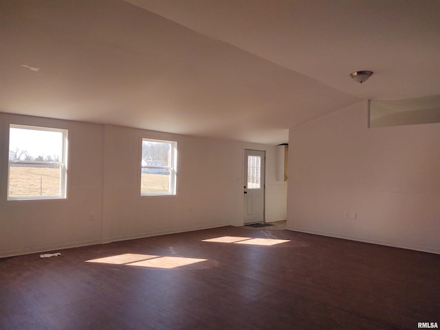 spare room featuring dark wood-style floors, lofted ceiling, and baseboards