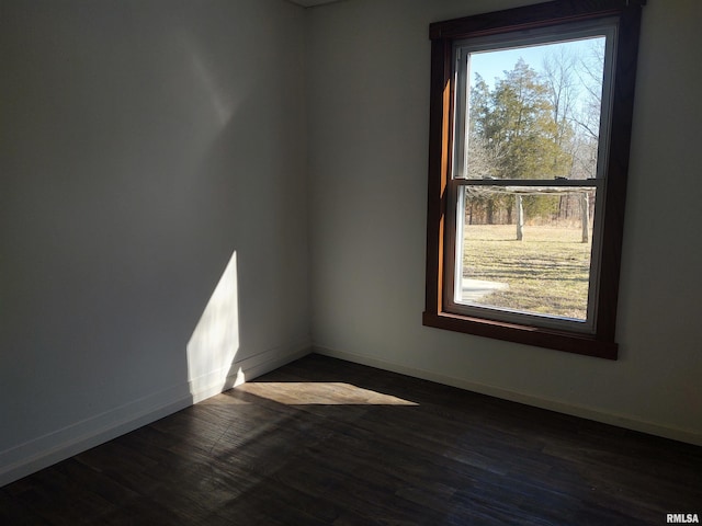 unfurnished room with dark wood-style floors, plenty of natural light, and baseboards