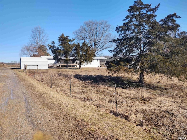 view of street with gravel driveway and a rural view