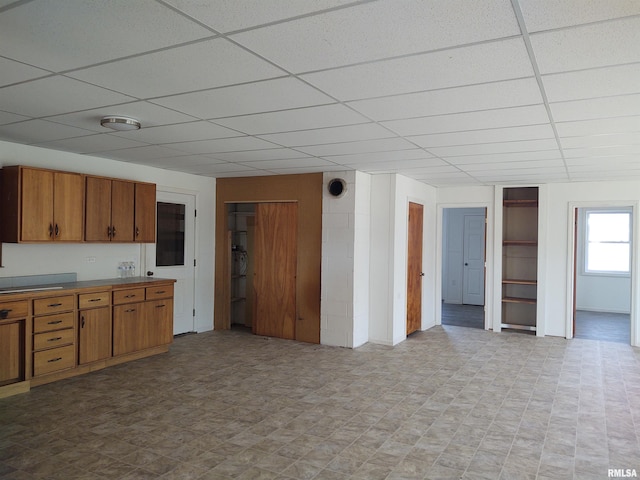 kitchen featuring light floors, a drop ceiling, light countertops, and brown cabinets