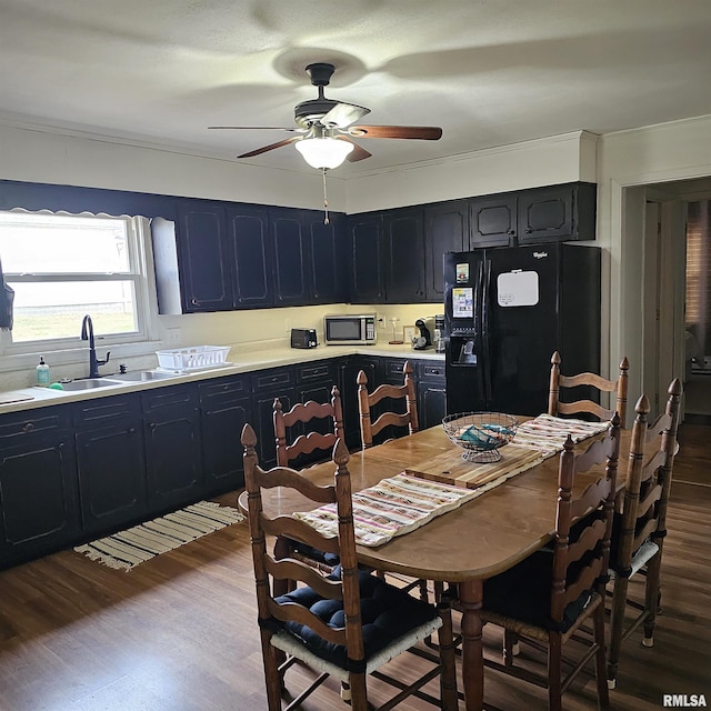 kitchen with light countertops, stainless steel microwave, black fridge with ice dispenser, and wood finished floors