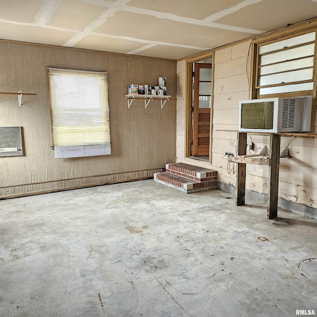 empty room featuring wood walls, cooling unit, and concrete flooring