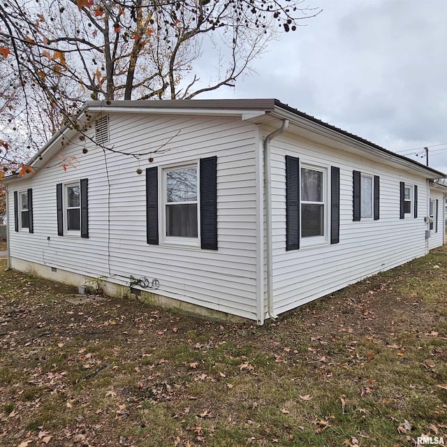 view of side of property with crawl space and a yard