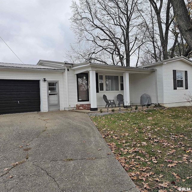 view of front of property with metal roof, a garage, covered porch, driveway, and a front lawn