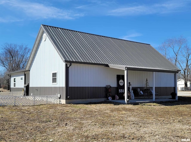 exterior space featuring fence, metal roof, and a lawn