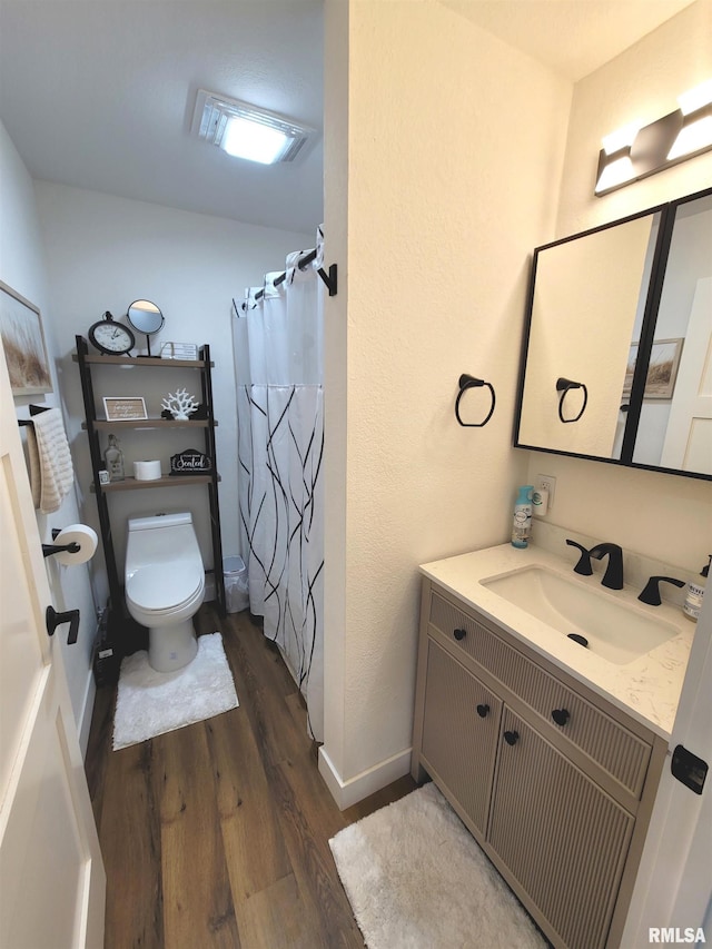 bathroom featuring curtained shower, toilet, wood finished floors, vanity, and baseboards