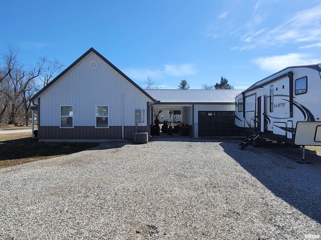 exterior space featuring driveway, an attached garage, and metal roof