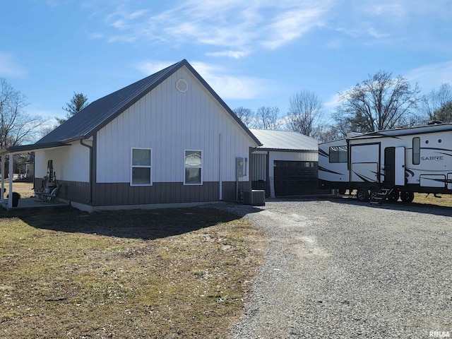 view of property exterior featuring metal roof, driveway, and cooling unit