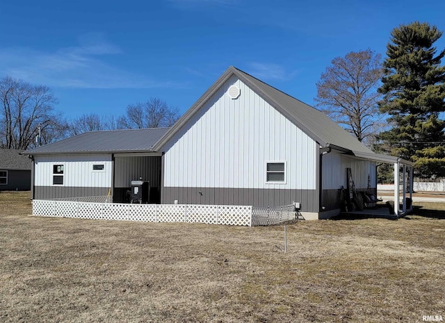 view of side of home featuring metal roof and a lawn