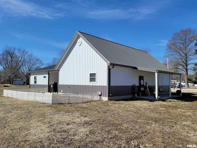 view of side of property featuring metal roof and a lawn