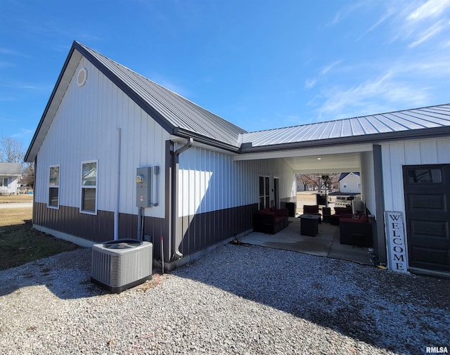 view of home's exterior with outdoor lounge area, central AC unit, and metal roof