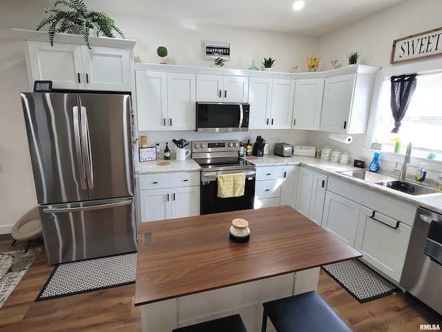 kitchen with a sink, appliances with stainless steel finishes, white cabinets, and dark wood-type flooring