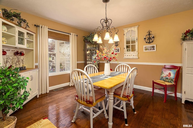 dining space with dark wood-type flooring, a chandelier, visible vents, and baseboards