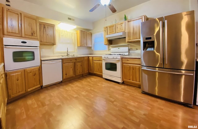 kitchen with under cabinet range hood, white appliances, a sink, visible vents, and light countertops