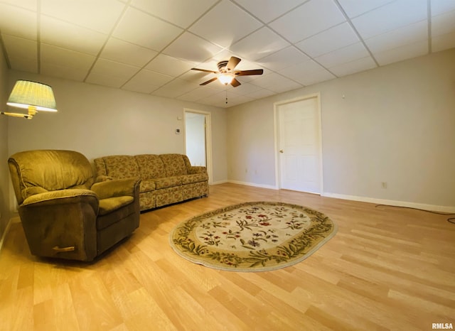 living area with a paneled ceiling, a ceiling fan, baseboards, and wood finished floors