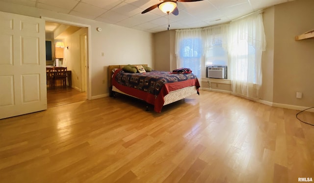 bedroom with a paneled ceiling, baseboards, and wood finished floors