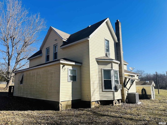 view of home's exterior with central AC and a chimney