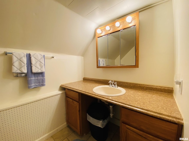 bathroom with lofted ceiling, tile patterned flooring, and vanity