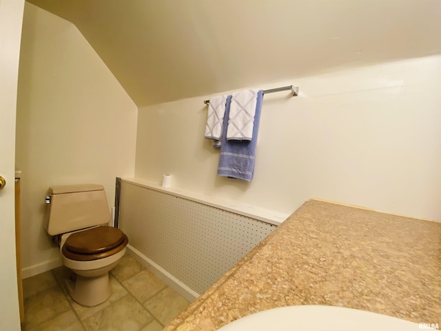 bathroom featuring toilet, baseboards, vaulted ceiling, and tile patterned floors