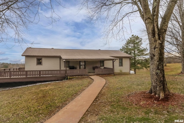 back of property with metal roof, a yard, and a deck