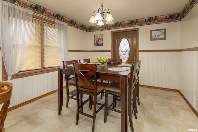 dining space with a notable chandelier and wainscoting