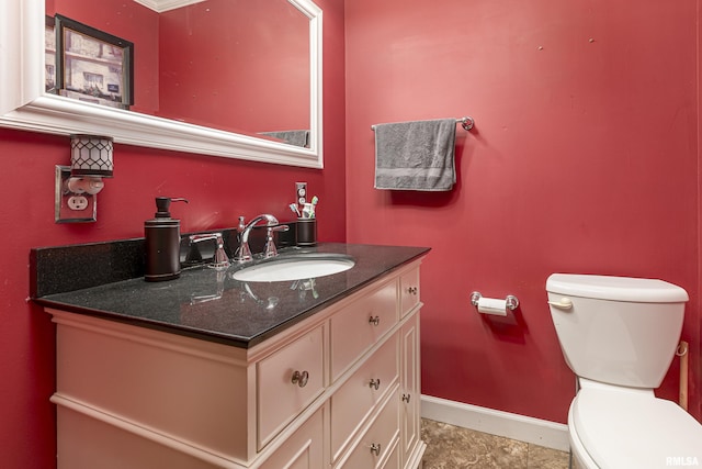 half bathroom with baseboards, vanity, and toilet