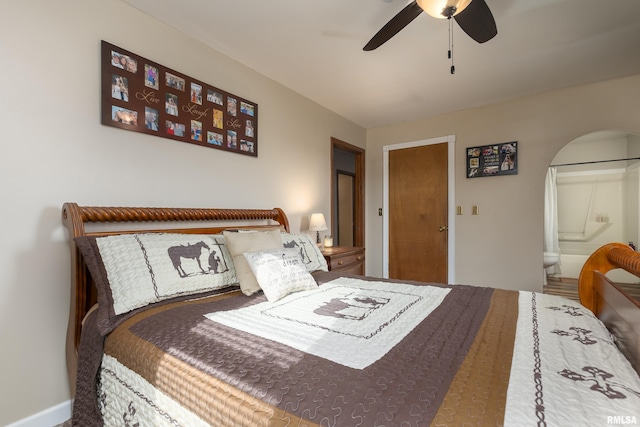 bedroom featuring a ceiling fan, arched walkways, and connected bathroom