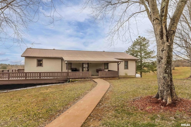 rear view of house featuring metal roof, a lawn, and a deck