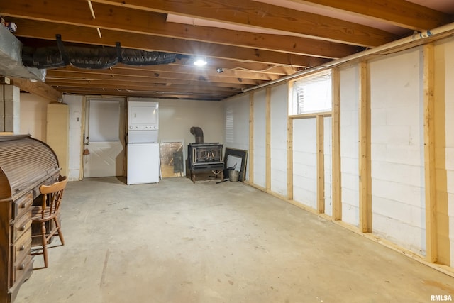 unfinished basement with stacked washer and dryer and freestanding refrigerator