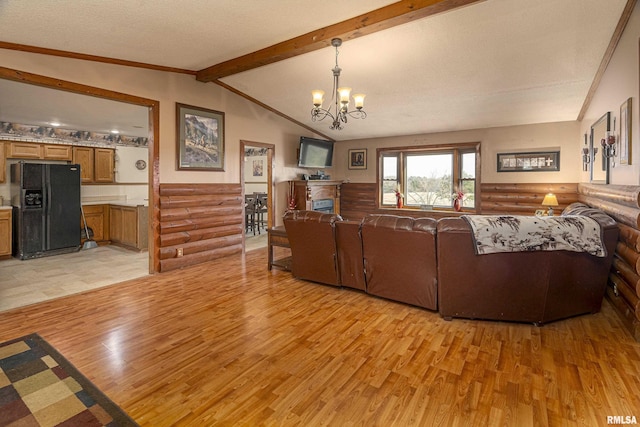 living area featuring light wood finished floors, vaulted ceiling with beams, log walls, a fireplace, and a chandelier