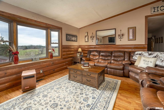 living area with lofted ceiling, light wood finished floors, a textured ceiling, and rustic walls