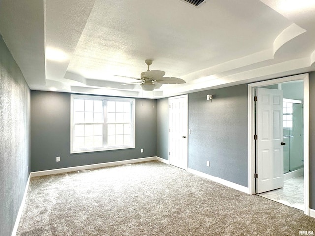 spare room featuring baseboards, a textured ceiling, a raised ceiling, and light colored carpet