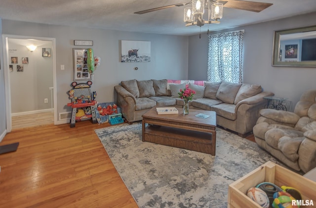 living area featuring a ceiling fan, baseboards, and wood finished floors