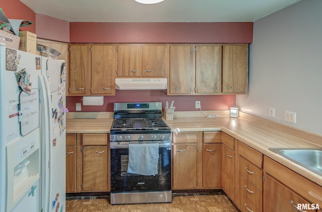 kitchen with stainless steel gas stove, under cabinet range hood, white refrigerator with ice dispenser, and light countertops