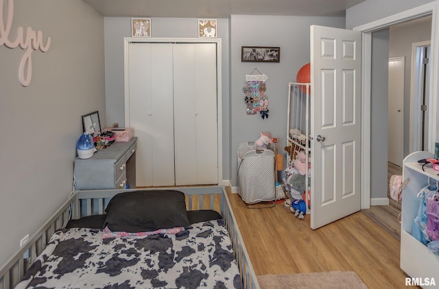 bedroom featuring light wood-type flooring, baseboards, and a closet