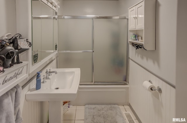 full bathroom featuring combined bath / shower with glass door, a sink, visible vents, and tile patterned floors