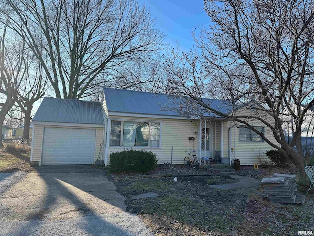 single story home featuring a garage, driveway, and metal roof