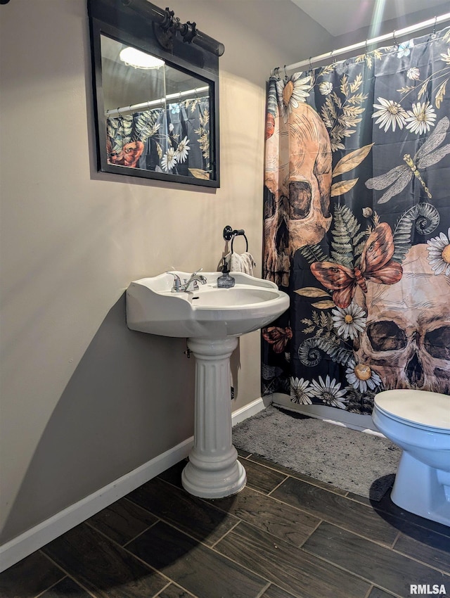 full bathroom with wood tiled floor, toilet, and baseboards